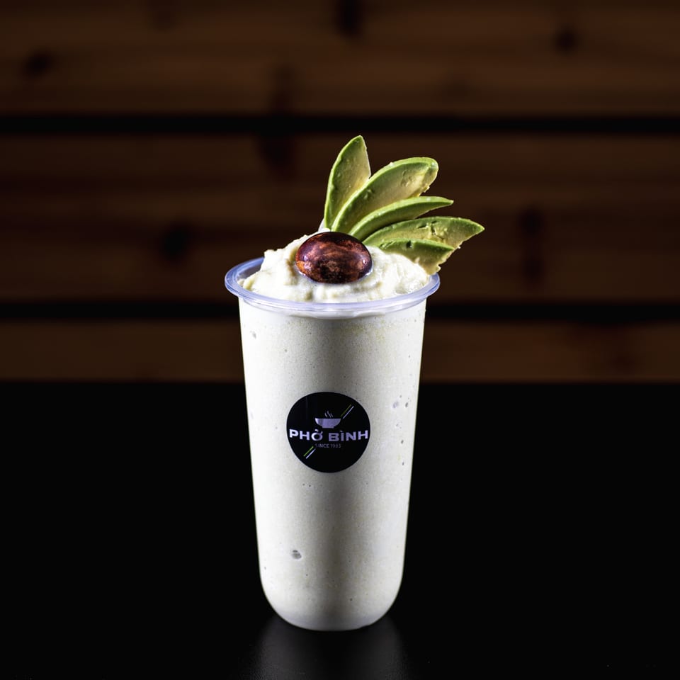 Pho Binh avocado smoothie with avocado slices and a dark brown seed on top.
